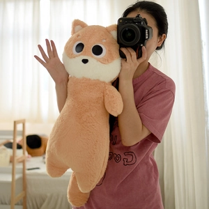 Detailed close-up of a long orange plush dog pillow with soft texture and cute facial features