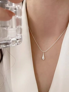 Polished silver teardrop pendant with fine snake chain on model for minimalist styling