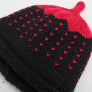 Close-up of heart jacquard pattern on black and red knit beanie with pointed crown