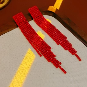 Close-up of elegant red tassel earrings with sparkling rhinestones and silver pins