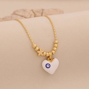 Macro d'un collier cœur doré avec émail œil bleu et breloques en forme d'étoile
