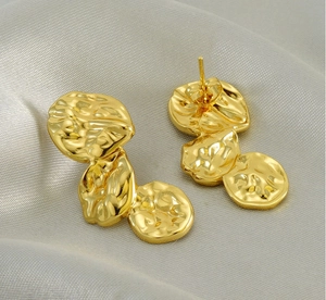 Detail of gold lava earrings with irregular hammered petal texture on silk background