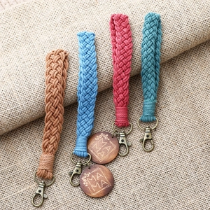 Handmade bohemian braided stripe wristlet keychains in four colors on burlap background