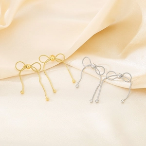 Détail macro de boucles d'oreilles nœud papillon en or et argent avec des franges élégantes