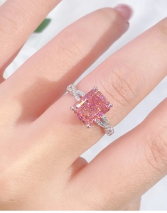 Detailed close-up of a pink sapphire silver ring with twisted diamond band on finger