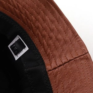 Close-up of brown faux leather bucket hat showing stitch detail and inner fabric lining
