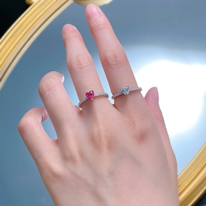 Close-up of elegant 925 silver heart rings with red and white stones on hand