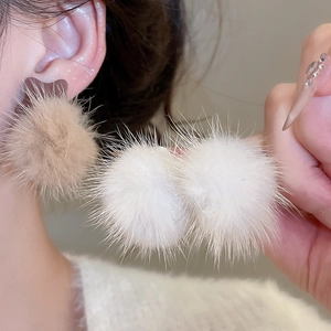 Detailed view of elegant plush ball earrings in brown and white with silver needle studs