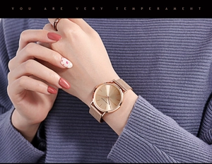 Detailed close-up of a rose gold mesh strap quartz watch on a model's wrist