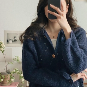 Detail of navy blue knit cardigan with plush texture, hollow weave and wooden buttons