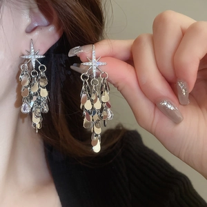 Détail de boucles d'oreilles étoiles argentées avec franges à gouttes multicouches