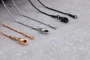 Macro view of gold, silver, and black metal necklace chains with lobster clasps