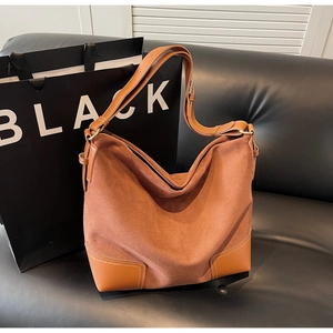 Detail of vintage suede tote bag showing brown leather patchwork and adjustable strap