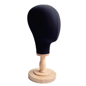 Detail of a black linen fabric mannequin head mounted on a natural wooden display stand base