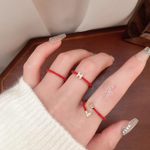 Close-up of red enamel H ring and gold nail ring with crystals on model finger