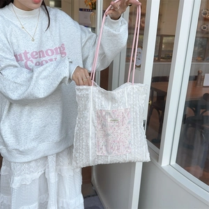 Detail of lace texture canvas tote bag with floral pocket and pink woven handles