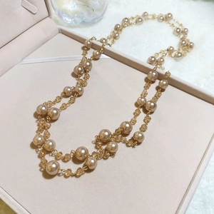 Detail of layered champagne pearl and crystal bead necklace on pink velvet jewelry box