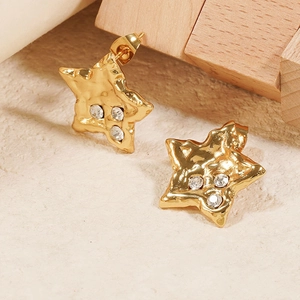 Vintage 18K gold star stud earrings with white zircons on a textured background