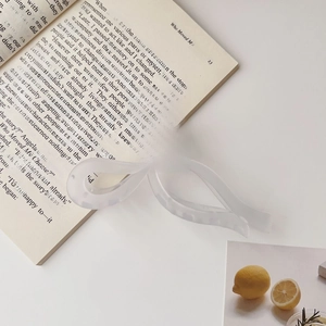 Detail of translucent frosted white bow hair claw clip placed on an open book