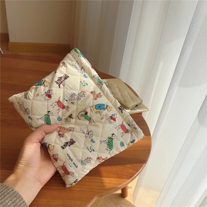 Detail of a cream quilted makeup bag featuring cute cartoon dog prints and a side label