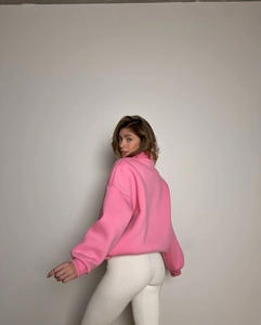 Detail view of pink half-zip sweatshirt and white ribbed leggings on model from the back