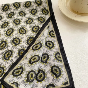 Detail of paisley square scarf with intricate black and yellow patterns and soft fabric