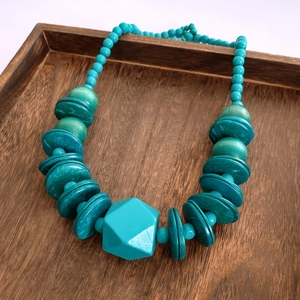Close-up of bohemian turquoise beaded necklace with geometric pendant on wooden tray
