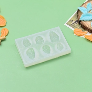 Detail showing 6-cavity leaf silicone mold on green surface for fondant cake decorating