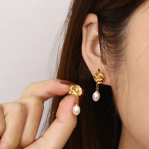 Élégantes boucles d'oreilles irrégulières en or avec perles blanches sur un modèle