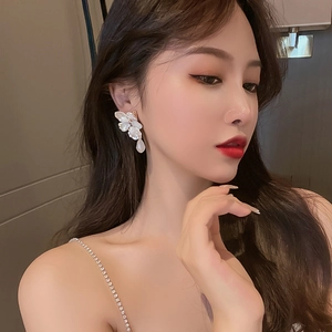 Elegant floral drop earrings with mother-of-pearl petals and a teardrop pearl on a model