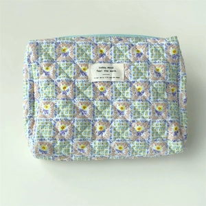 Detailed view of blue floral quilted cotton makeup bag with zip closure and fabric label