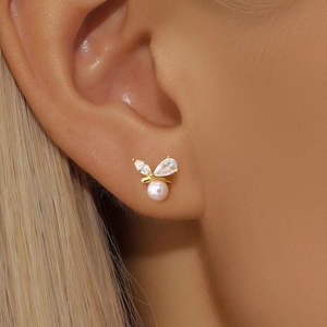 Detailed macro shot of a butterfly stud earring with white pearl and sparkling zircons