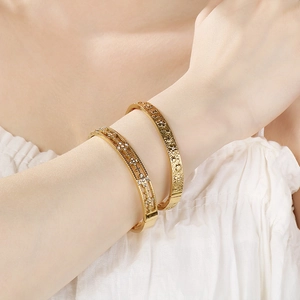 Close-up of 18K gold plated hollow diamond and floral relief bangles on female wrist