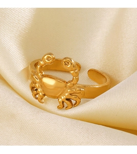 Gros plan d'une bague crabe dorée ajustable sur un fond élégant en soie champagne