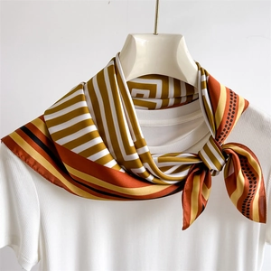 Détail d'un foulard en satin de soie de 70cm avec motifs géométriques sur un t-shirt blanc