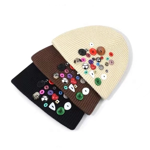 Vue détaillée de bonnets en tricot noir marron et crème avec boutons décoratifs colorés