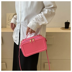 Detail of fuchsia suitcase-style handbag with embossed fashion lettering and gold hardware