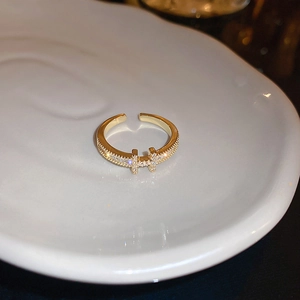 Close-up of gold plated adjustable ring with zircon H-letter on a white ceramic tray