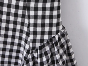 Close-up detail of black and white gingham pattern with elegant ruffled texture and smocking
