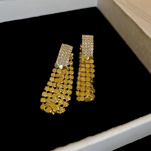 Macro detail of gold sequin tassel earrings with sparkling rhinestones in a jewelry box