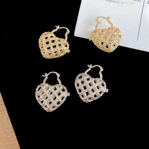 Close-up of gold and silver hollow heart-shaped hoop earrings with mesh pattern