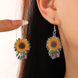 Boucles d'oreilles bohèmes tournesol avec pendentifs en acrylique portées par un modèle
