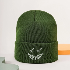 Close-up of dark green ribbed knit beanie featuring a white embroidered smiley face design