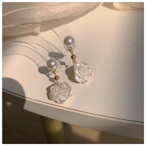 Detail of camellia flower earrings with white pearl and gold finish in a macro view