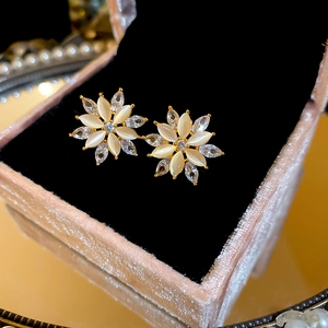 Macro shot of gold flower earrings with opal and zircon in a pink velvet jewelry box