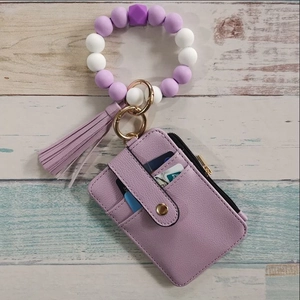 Detail view of purple silicone bead bracelet with PU leather wallet and tassel on wood