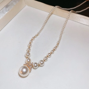 Gros plan d'un collier de perles vintage français avec fermoir en V doré dans un écrin