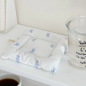 Detailed view of quilted cotton coaster with blue bow print on minimalist white desk