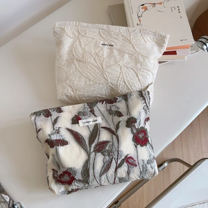 Macro detail of French floral embroidery on beige fabric pouches with Simple Wish labels