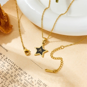 Detail of gold star pendant with letter A on vintage book background